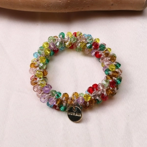 Close-up of colorful faceted crystal beads and gold MORAVA logo charm on elastic hair tie