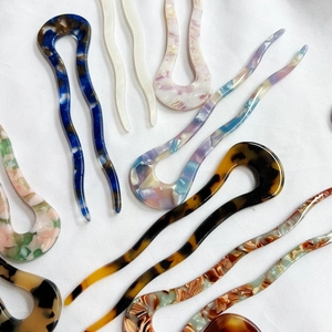 Elegant U-shaped acetate hair pins in various marble colors on white fabric