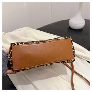 Detail view of leopard print crossbody bag showing brown leather base and fine stitching