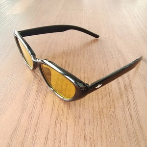 Detail of retro cat-eye kids sunglasses with amber lenses on a wooden surface