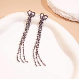 Macro shot of long purple rhinestone tassel earrings with interconnected hollow heart design