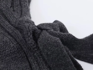 Close-up of dark grey knitted fabric showing fine texture and knotted tie detail