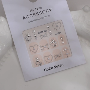 Detail of 3D nail art kit with white bows, pearls, and golden hearts on pink backing