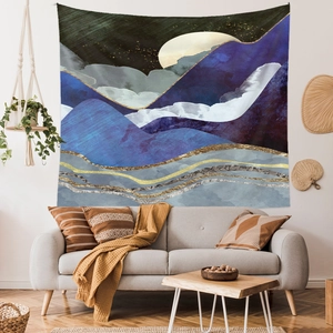 Detail of abstract blue mountain tapestry with gold textures above a modern sofa