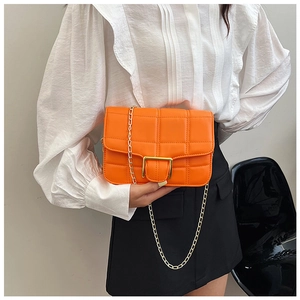 Close-up of orange quilted crossbody bag with golden chain strap and metal buckle