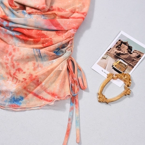 Détail de la robe en maille tie-dye avec cordons latéraux et imprimés abstraits orange
