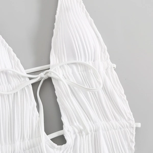 Dettaglio di un costume da bagno bianco con texture a pieghe verticali e lacci regolabili