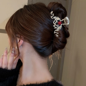 Golden dragon hair claw clip with a red bead shown in a model's long hair