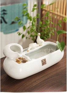 Detail of white ceramic indoor fountain with two duck figures and oriental lettering