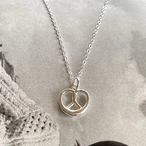 Macro shot of 925 sterling silver pretzel heart pendant necklace on a grey knit surface