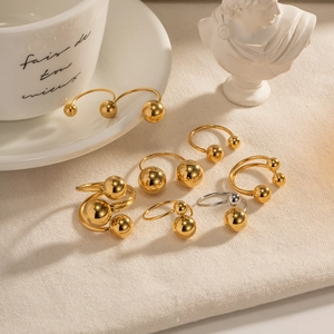 Minimalist gold and silver spherical steel rings set displayed on a textured fabric background