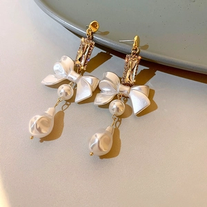 Detailed view of gold bow earrings featuring rectangle rhinestones and baroque pearls