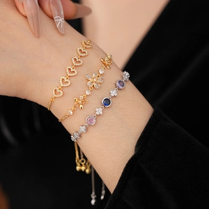 Gros plan sur un ensemble de trois bracelets dorés avec fleurs et cœur en zircon