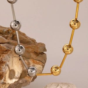 Modern 18k gold and silver two-tone stainless steel ball chain necklace on a rock base