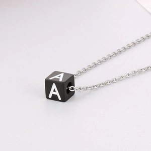 Gros plan d'un collier en acier titane avec pendentif carré noir orné de la lettre A