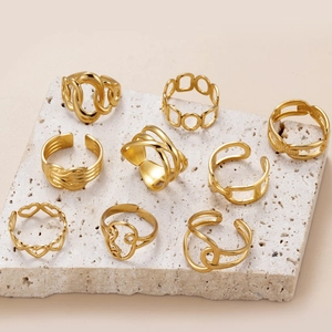 Collection of golden heart and geometric hollow titanium steel adjustable rings on stone