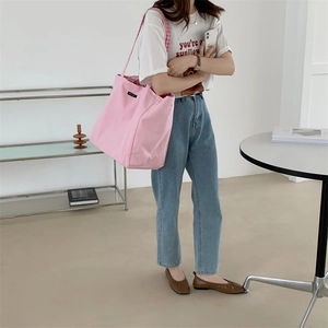 Detailed view of pink canvas tote bag with stylish checkered strap worn by a model