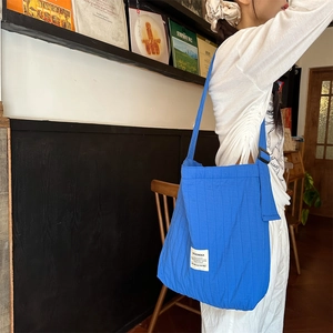 Detail of blue striped quilted canvas tote with adjustable strap on white outfit