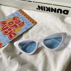 Close-up of retro cat-eye sunglasses with white frame and light blue lenses on fabric