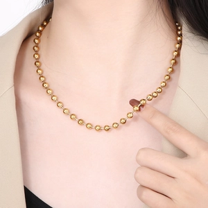 Fashionable gold stainless steel beaded ball chain necklace worn by a female model