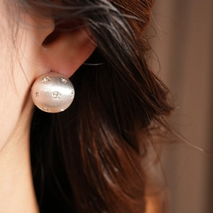 Zoom sur puce d'oreille dôme en argent brossé avec cristaux en forme d'étoile scintillante
