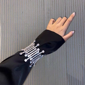 Macro shot of sleeve cuffs featuring luxury rhinestone fringes on black satin fabric