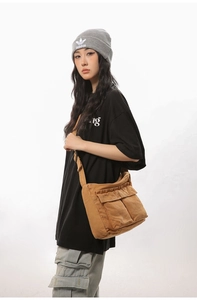 Detail shot of large khaki canvas messenger bag with double pockets on female model