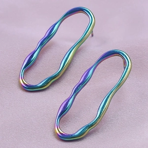 Iridescent wavy oval stainless steel earrings on elegant pink silk background