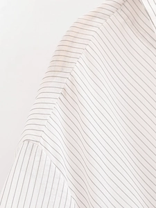 Detailed view of stitching on a white pinstripe shirt featuring premium woven fabric