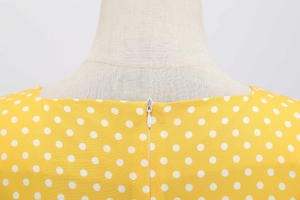 Close-up of invisible back zipper on yellow polka dot retro dress with woven texture