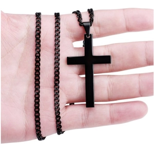 Close-up of a hand holding a black metal cross pendant with a matching chain