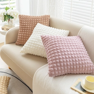 Three square bubble texture pillows in pink, cream, and brown on a soft sofa
