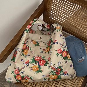 Floral canvas tote bag with red and yellow flowers on a vintage rattan chair