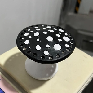 Detail view of a black mushroom earring organizer with white dots on a scale