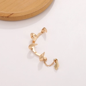 Detailed view of a gold-tone devil fang ear cuff featuring a sharp claw design and chain