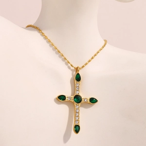 Pendentif croix en acier plaqué or 18K avec zircon vert sur un mannequin blanc
