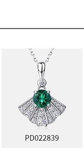 Macro shot of a fan-shaped silver necklace with a green emerald and white pavé accents