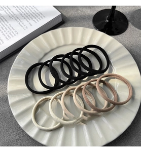 Detail of 10-piece elastic hair ties in neutral tones on a ceramic plate