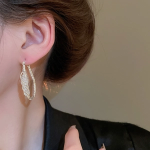 Close-up of minimalist silver mesh hoop earrings with twisted rope texture and pavé detail
