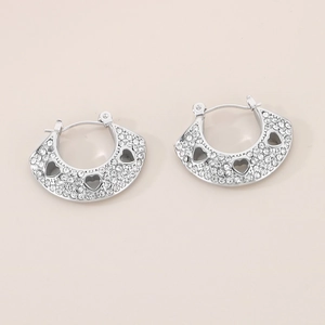 Détail de boucles d'oreilles vintage argentées avec cœurs ajourés et strass brillants