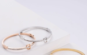 Detailed view of three stackable heart bangles in gold, silver, and rose gold plating
