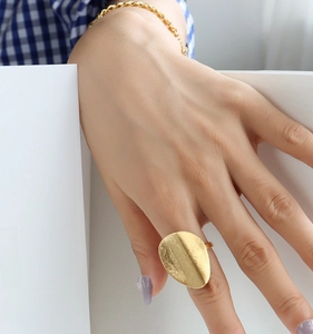 Macro shot of oversized matte gold ring with brushed texture on a model's finger