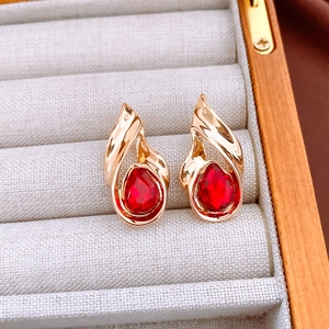 Detail of vintage teardrop earrings with red gems in gold setting on a velvet display box