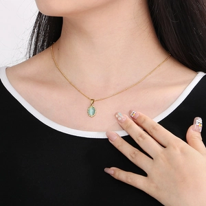 Close-up of a gold stainless steel lace necklace with a green cat-eye opal on a model