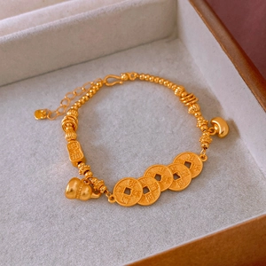 Detail of gold gourd and coins bracelet with Nafu charm on gray velvet jewelry box