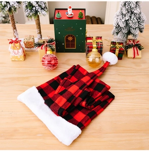 Detail of red and black plaid plush Santa hat on a wooden desk with festive ornaments