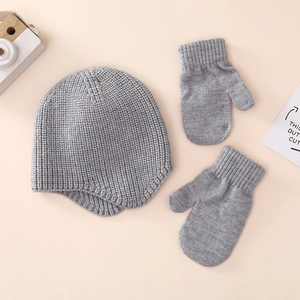 Close-up detail of grey knitted baby winter hat and matching gloves with soft texture