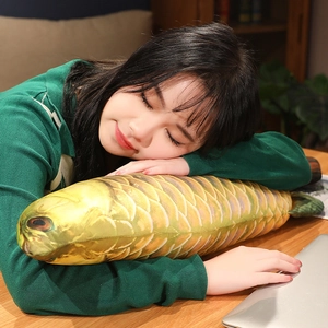 Asian woman resting on a desk hugging a realistic golden fish plush pillow shell