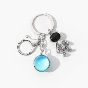 Detail of silver astronaut pendant and blue planet glass dome on key ring