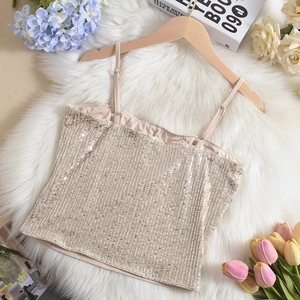 Detail of champagne gold sequin camisole top hanging on a wooden hanger with flowers